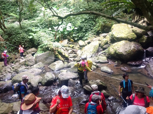 Guide helping hikers passing a creek